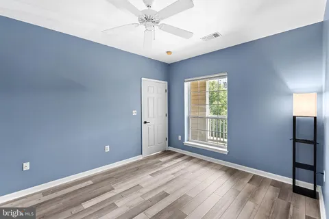 a view of an empty room with window and wooden floor