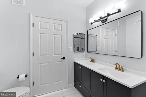 a bathroom with a sink vanity granite toilet and a mirror