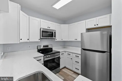 a kitchen with white cabinets and stainless steel appliances