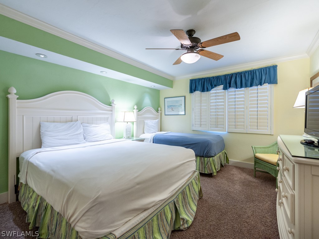 2445 West Gulf Drive, Unit E2 Sanibel, FL 33957 - Photo 26 of 35 a bedroom with a bed and a chandelier