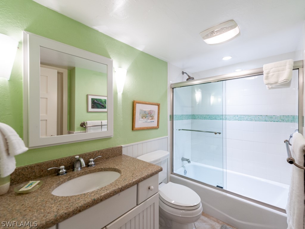 2445 West Gulf Drive, Unit E2 Sanibel, FL 33957 - Photo 28 of 35 a bathroom with a granite countertop sink toilet a mirror and shower