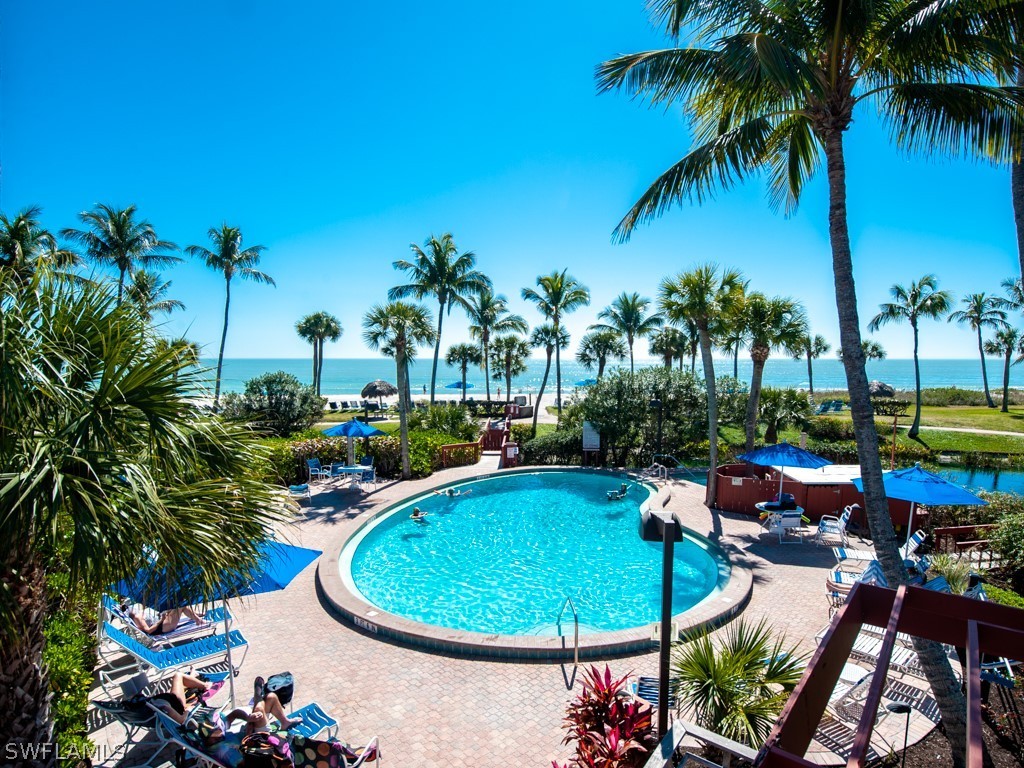 2445 West Gulf Drive, Unit E2 Sanibel, FL 33957 - Photo 31 of 35 a view of a swimming pool with lawn chairs under an umbrella