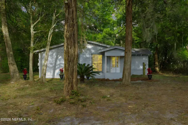 a view of a house with a yard and large tree