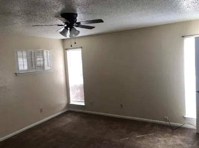 an empty room with a window and a fan