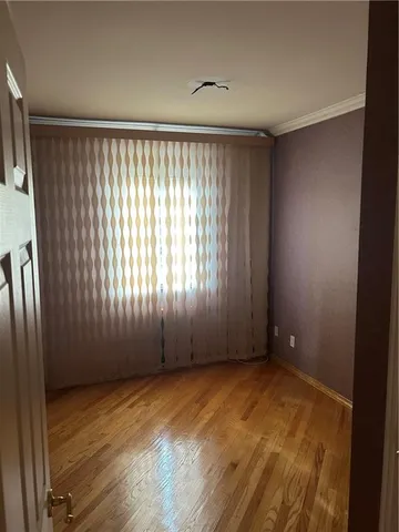 an empty room with wooden floor and windows with curtains