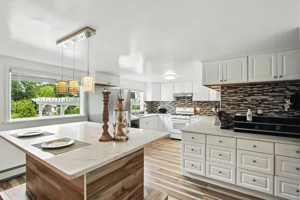 a kitchen with white cabinets and window