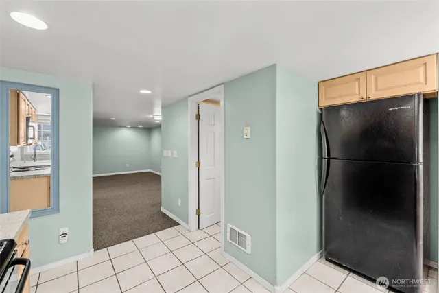 a view of a refrigerator in kitchen and an empty room