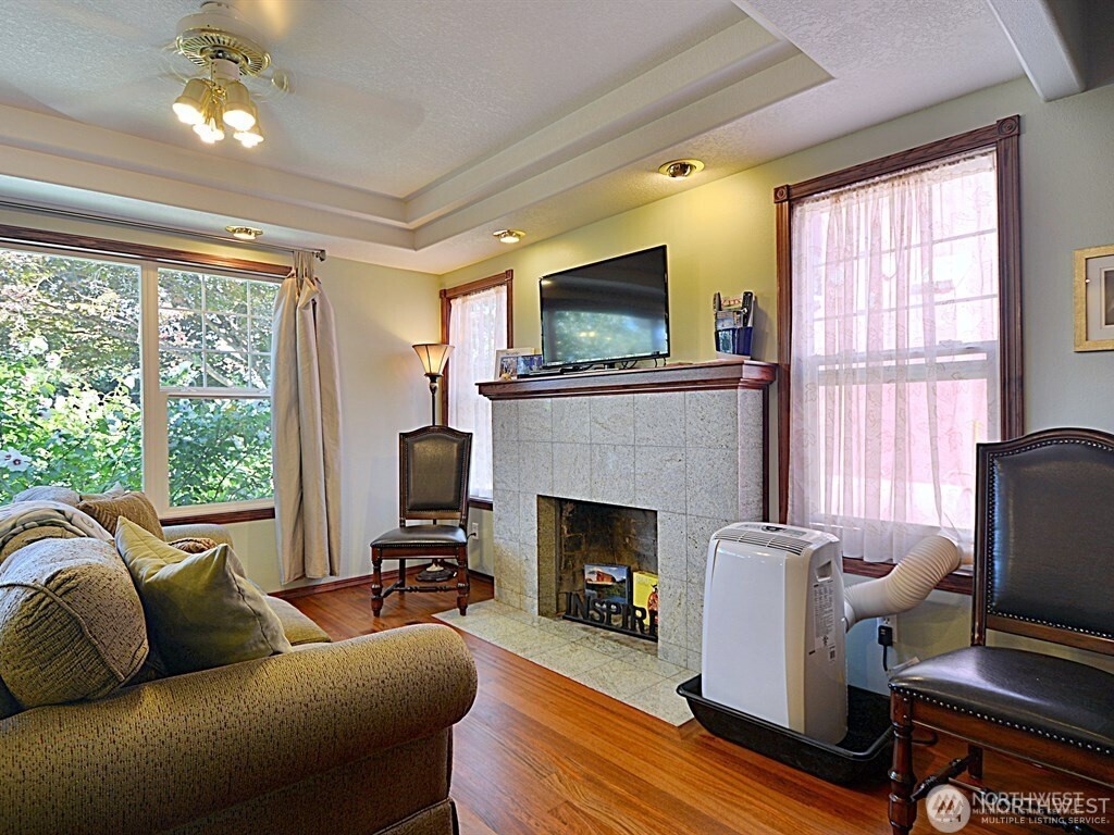 7842 Lake City Way Northeast Seattle, WA 98115 - Photo 7 of 36 a living room with furniture a flat screen tv and a fireplace
