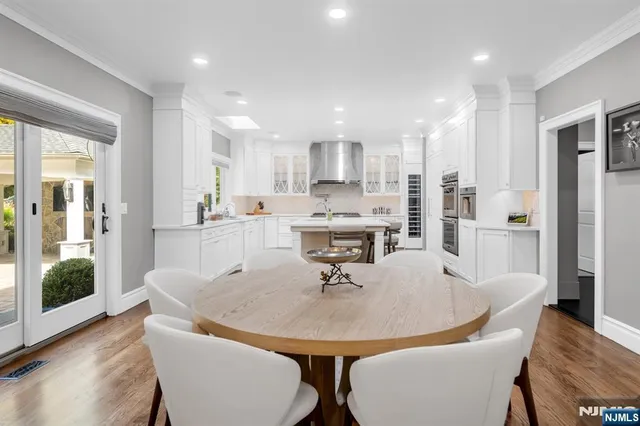 a kitchen with stainless steel appliances a dining table chairs and wooden floor