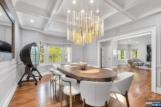 a dining room with wooden floor a chandelier a wooden table and chairs