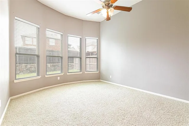 an empty room with chandelier fan and windows