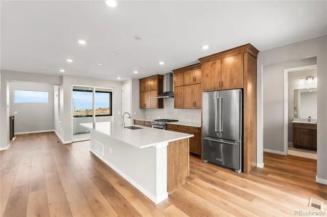 a kitchen with stainless steel appliances granite countertop a refrigerator a sink dishwasher a stove and a refrigerator with wooden floor