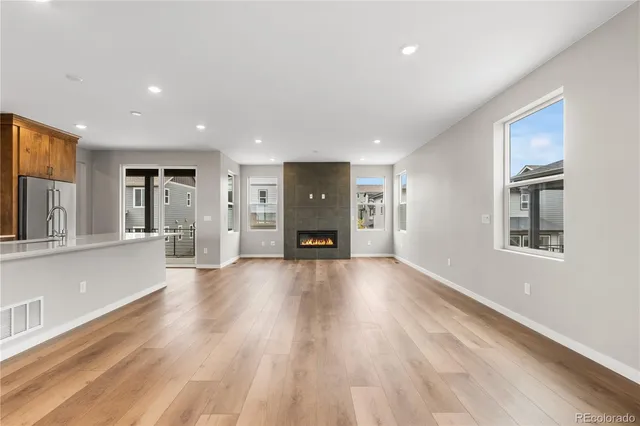 a view of a big room with wooden floor and a kitchen