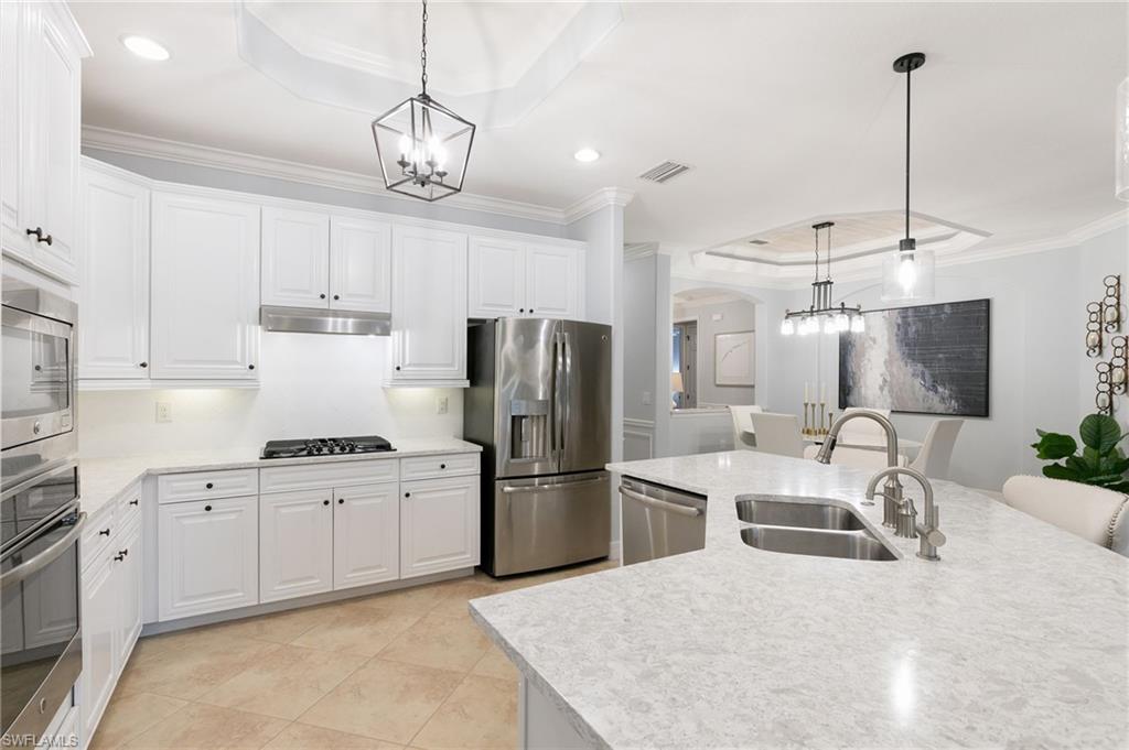2862 Aviamar Circle Naples, FL 34114 - Photo 12 of 48 Kitchen featuring a raised ceiling, ornamental molding, appliances with stainless steel finishes, white cabinetry, and arched walkways