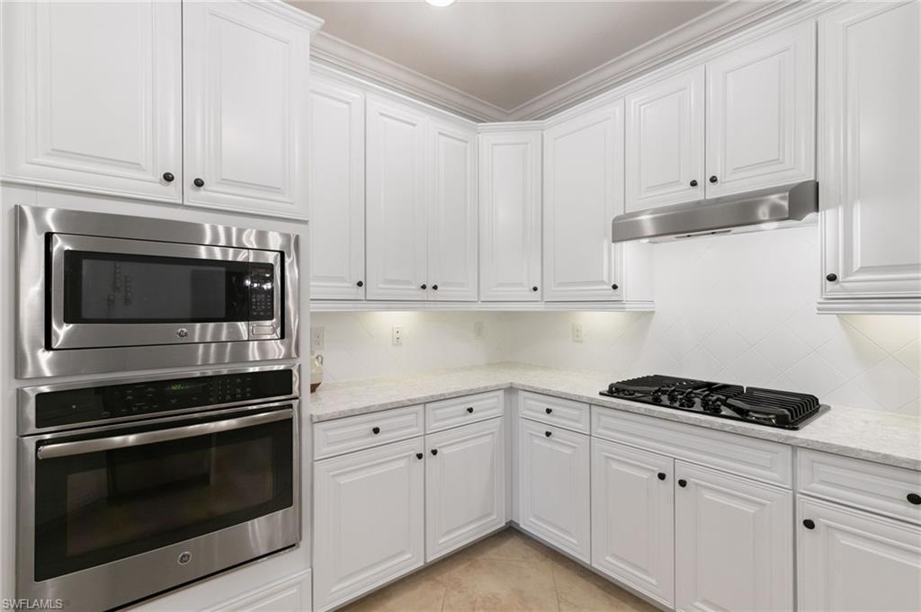 2862 Aviamar Circle Naples, FL 34114 - Photo 13 of 48 Kitchen featuring white cabinets, stainless steel appliances, light stone counters, under cabinet range hood, and decorative backsplash