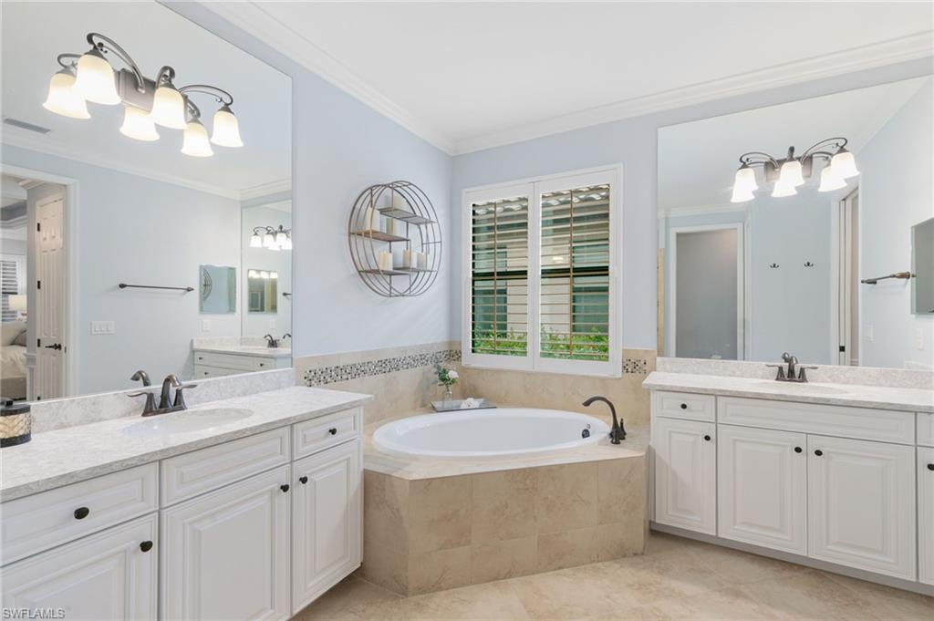 2862 Aviamar Circle Naples, FL 34114 - Photo 20 of 48 Ensuite bathroom featuring a bath, two vanities, ornamental molding, and light tile patterned floors