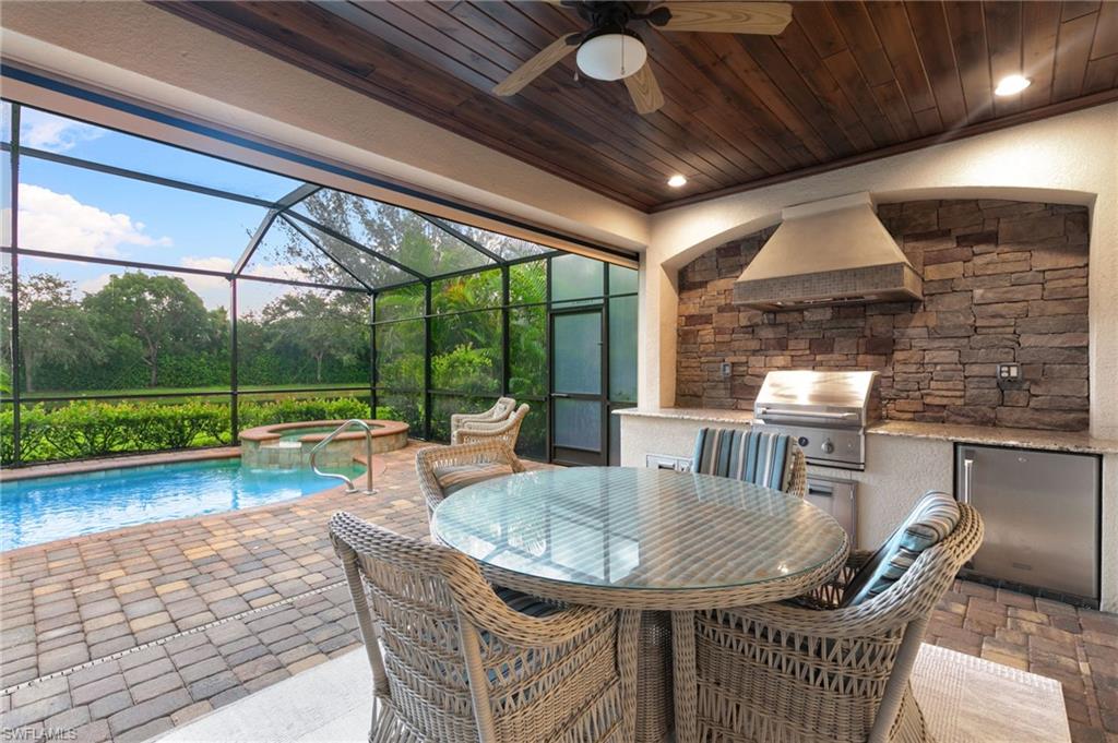 2862 Aviamar Circle Naples, FL 34114 - Photo 30 of 48 View of patio featuring an outdoor kitchen, outdoor dining space, a pool with connected hot tub, a sunroom, and ceiling fan
