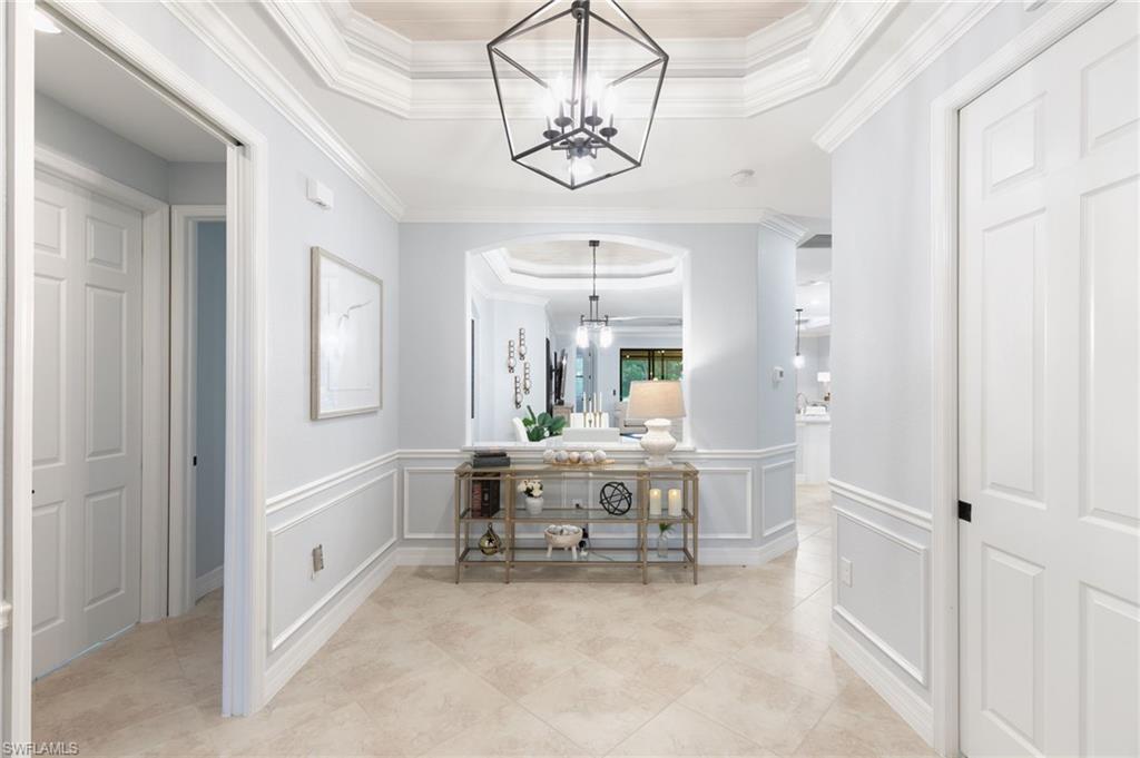 2862 Aviamar Circle Naples, FL 34114 - Photo 5 of 48 Hall featuring a raised ceiling, a chandelier, crown molding, light tile patterned floors, and a decorative wall