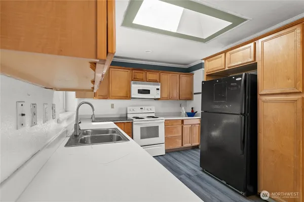 a kitchen with stainless steel appliances granite countertop a refrigerator a sink dishwasher a stove a dining table and chairs with wooden floor