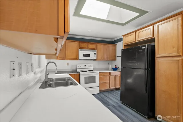 a kitchen with stainless steel appliances granite countertop a refrigerator a sink dishwasher a stove a dining table and chairs with wooden floor