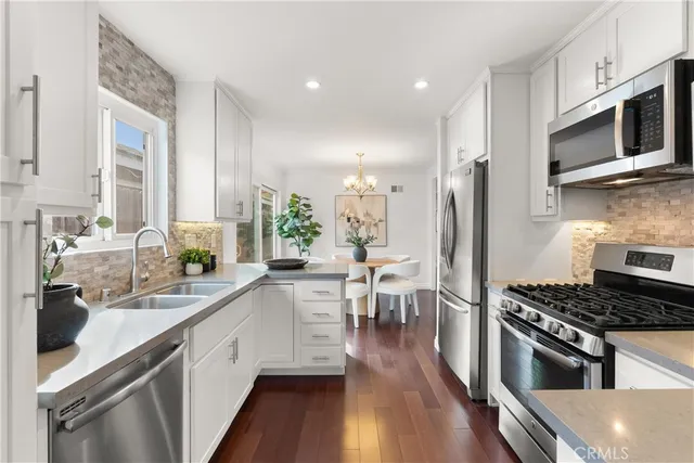 a kitchen with stainless steel appliances a sink a stove top oven a counter space and cabinets