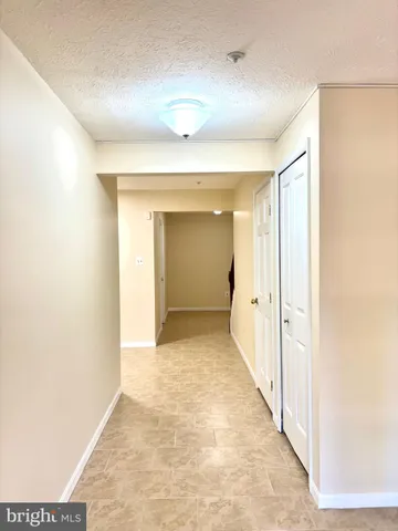 a view of a hallway with wooden floor and a bathroom