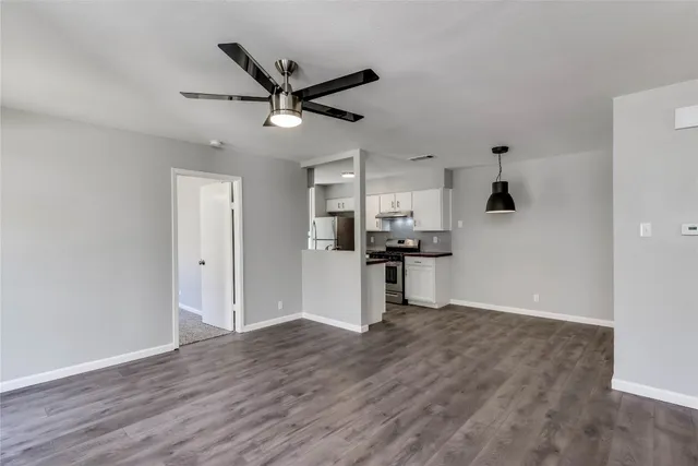 a living room with stainless steel appliances kitchen island hardwood floor and a ceiling fan