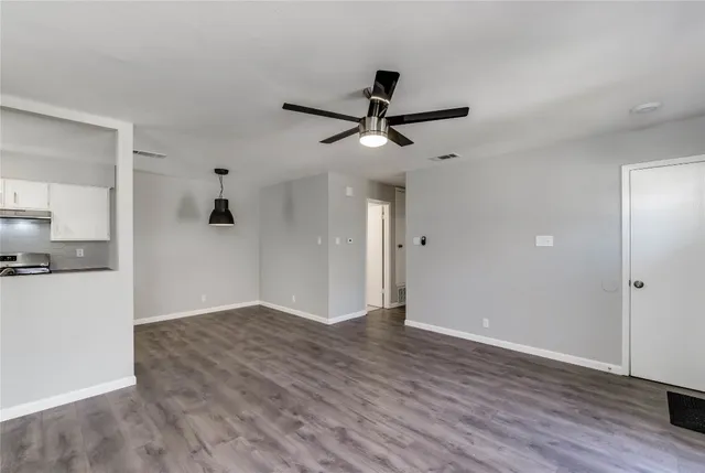 a view of empty room with wooden floor and ceiling fan