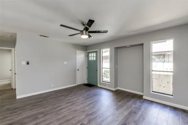 a view of an empty room with wooden floor and a window