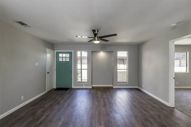a view of an empty room with wooden floor and a window