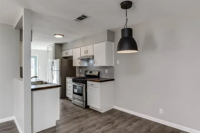 a kitchen with stainless steel appliances granite countertop a sink a stove a refrigerator and island with wooden floor