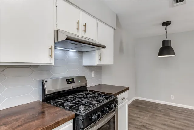 a kitchen with granite countertop a stove and a wooden floor