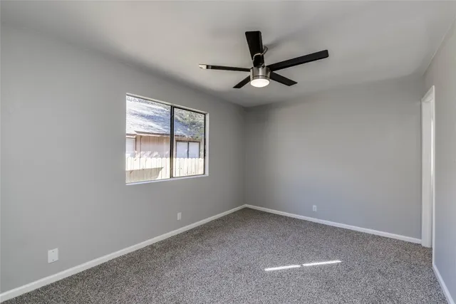 a view of a big room with a ceiling fan and windows