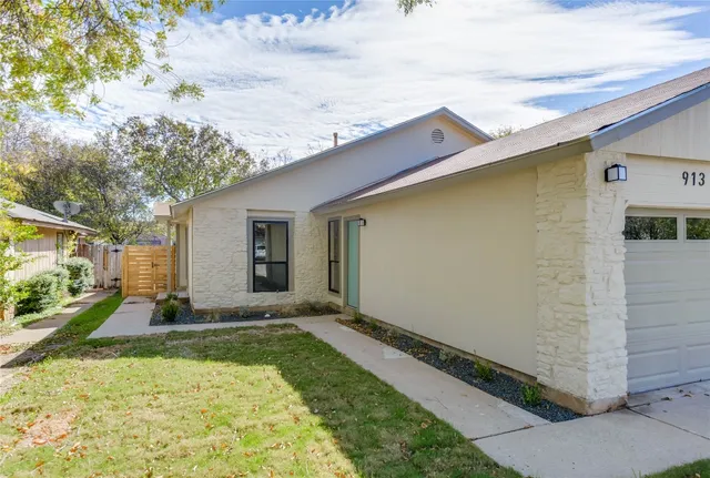 a backyard of a house with potted plants and large tree