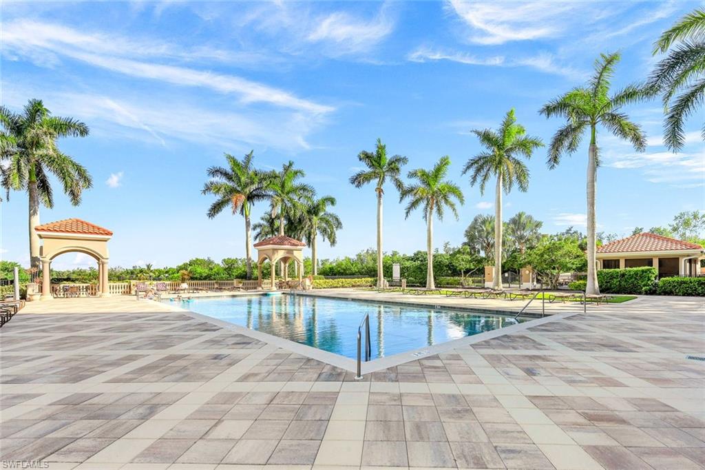 1060 Borghese Lane, Unit 2002 Naples, FL 34114 - Photo 20 of 22 a view of a swimming pool with a lawn chair and palm tree