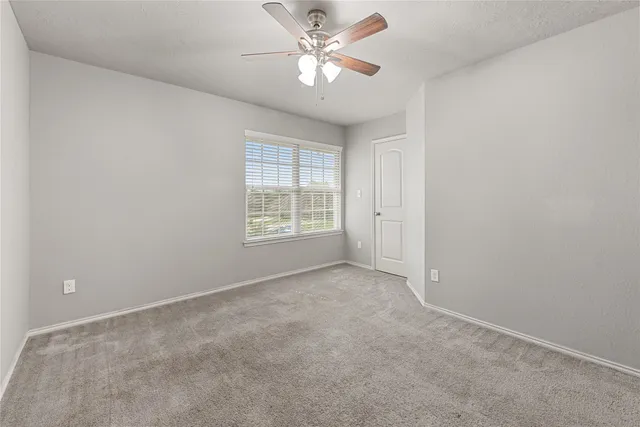 an empty room with windows and fan