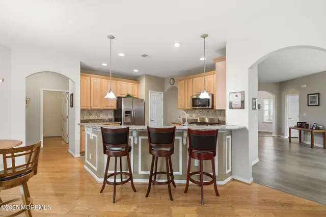 a kitchen with stainless steel appliances kitchen island granite countertop a dining table chairs and white cabinets