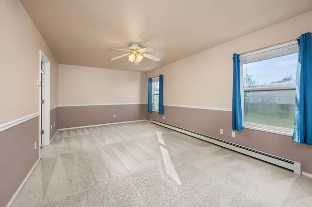 an empty room with windows and fan