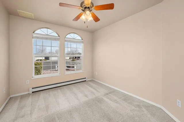 an empty room with chandelier fan and windows