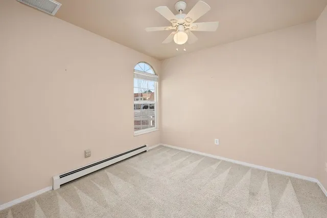 an empty room with windows and fan