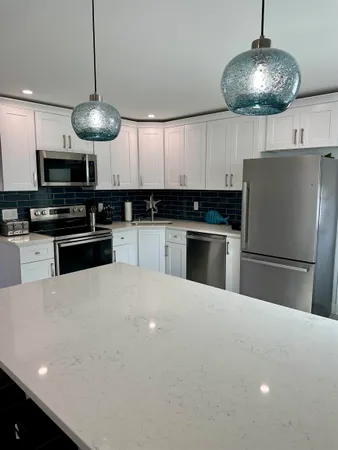 a kitchen with stainless steel appliances a table a refrigerator a stove a microwave oven a sink dishwasher and a refrigerator