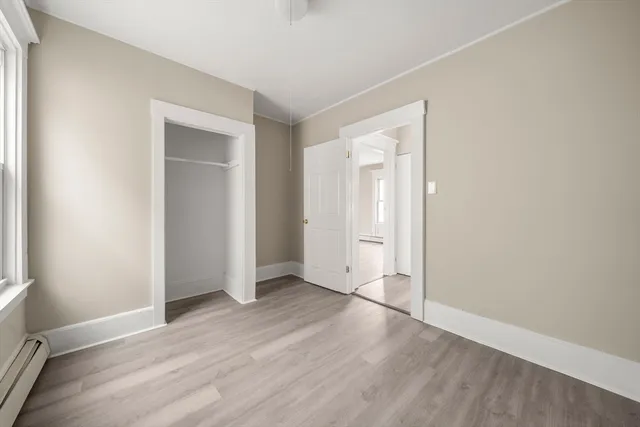 an empty room with wooden floor & closet and windows