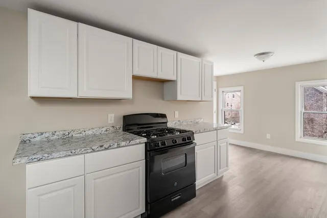 a kitchen with granite countertop white cabinets and a stove
