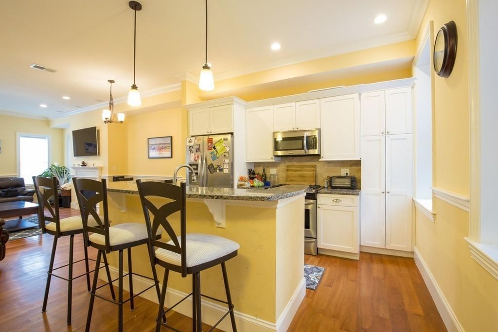 8 Gates Street, Unit 1 Boston, MA 02127 - Photo 2 of 14 a open kitchen with stainless steel appliances granite countertop a refrigerator a stove top oven a sink dishwasher and white cabinets with wooden floor