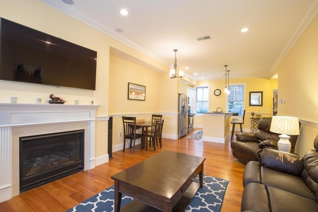 8 Gates Street, Unit 1 Boston, MA 02127 - Photo 3 of 14 a living room with furniture a flat screen tv and kitchen view