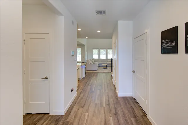 a kitchen with stainless steel appliances granite countertop a stove top oven a sink a dining table and chairs with wooden floor