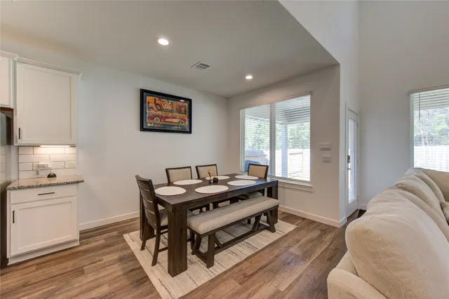 a living room with stainless steel appliances a dining table and chairs
