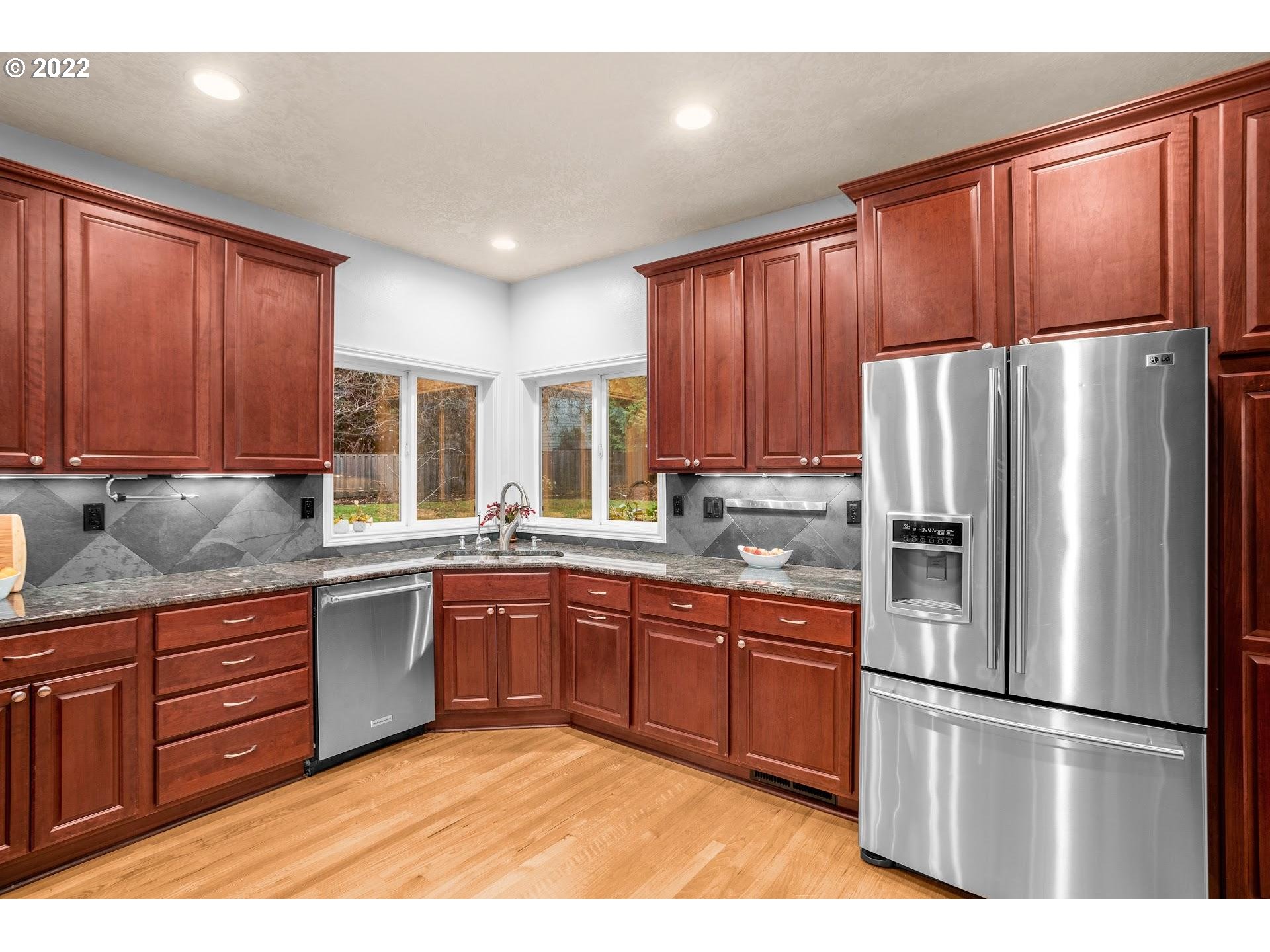 16625 Southwest Springwater Court Beaverton, OR 97006 - Photo 11 of 32 a kitchen with stainless steel appliances granite countertop a refrigerator a sink dishwasher a stove with wooden cabinets and floor