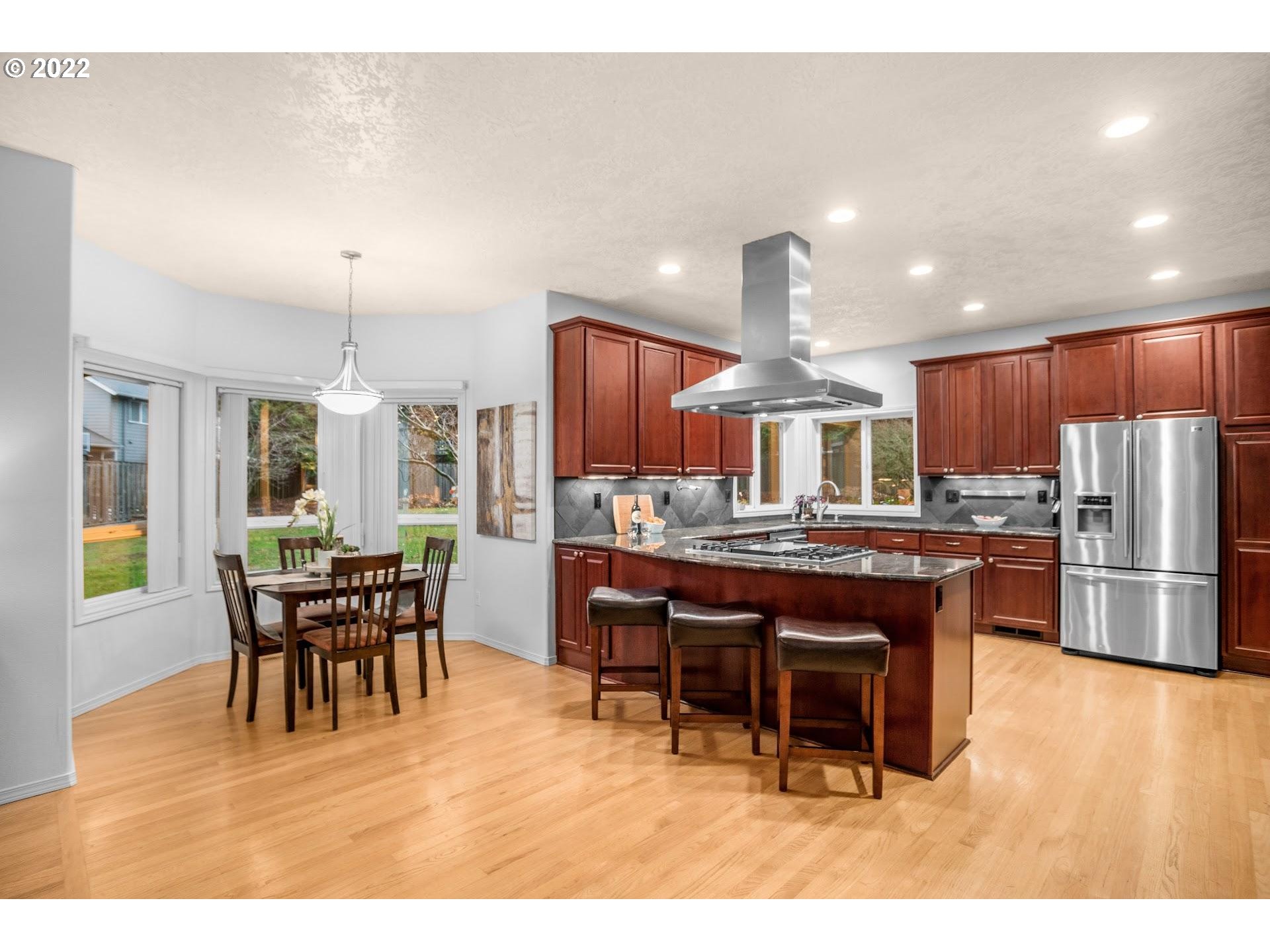 16625 Southwest Springwater Court Beaverton, OR 97006 - Photo 12 of 32 a dining hall with stainless steel appliances kitchen island granite countertop a dining table and chairs