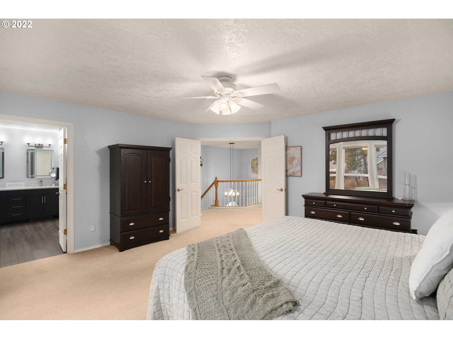 16625 Southwest Springwater Court Beaverton, OR 97006 - Photo 20 of 32 a bedroom with a bed and a chandelier